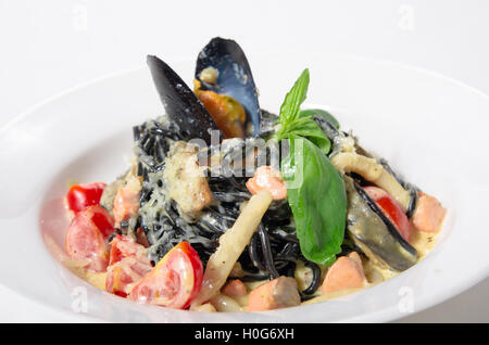 Spaghetti al nero di seppia, cozze, gamberi, calamari in una salsa cremosa con parmigiano Foto Stock