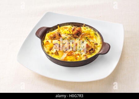 Il pollo e la pancetta salsa alla panna al gratin su piastra bianca sullo sfondo Foto Stock
