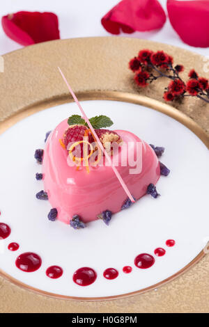 Gelatina di rosa torta a forma di cuore con bacche rosse e il cioccolato sul piatto bianco Foto Stock