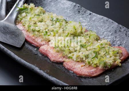 Fresche di lingua di maiale con salsa di cipolle sul piatto nero Foto Stock