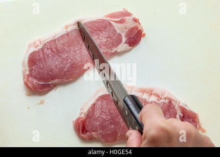 Il taglio fresco di manzo crudo con coltello in cucina Foto Stock