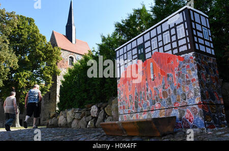 Passanti a piedi passato una giunzione scatola dipinta con i suini in Kalbe/Milde, Germania, 13 settembre 2016. La città si sta trasformando in un cente di attrazione per persone creative come "artista città Kalbe'. Foto: Jens KALAENE/dpa Foto Stock