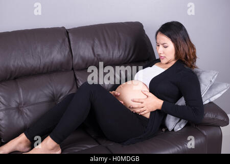 Donna incinta di ottenere una contrazione nel salotto di casa Foto Stock
