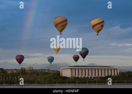 I palloni ad aria calda che passa sopra il Lago Burley Griffin e Australian National Library durante il balloon festival Canberra Australia Foto Stock