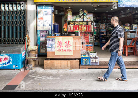 Un uomo cammina davanti ad una farmacia cinese nell'alloggiamento estate in Geylang Bahru in Singapore Foto Stock