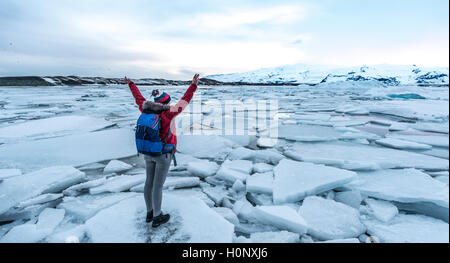 Donna in piedi sul ghiaccio floe, Jökulsárlón laguna glaciale, bordo meridionale del Vatnajökull, Regione meridionale Islanda Foto Stock