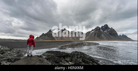 Escursionista guardando le montagne Klifatindur, Eystrahorn e Kambhorn, Stokksnes capezzagna, Klifatindur mountain range, Regione orientale Foto Stock