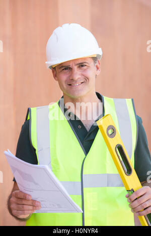 Ritratto di lavoratore edile sul sito di costruzione con casa piani Foto Stock