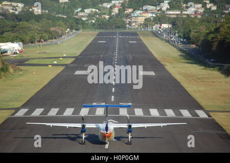 Aereo che decollo a Santa Lucia, Airport Runway con case alla fine della pista George F.L. Aeroporto Charles, Foto Stock