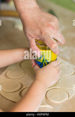 I bambini e i papà cuocere le mani i cerchi di pasta Foto Stock