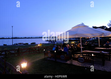 Persone sedute in un ristorante lungo il lago Ryn nella città di Ryn situato tra il lago Ryn e il lago Ołow nel Voivodato Warmian-Masuriano. Polonia Foto Stock