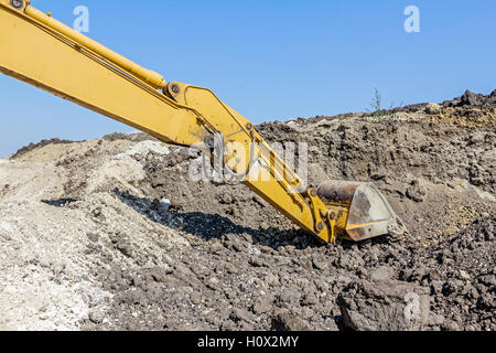 Escavatore giallo è terreno di scavo tirando verso massa sul sito in costruzione, il progetto in corso. Foto Stock