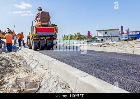 Piccolo schiacciasassi è opacizzazione di nuova strada fatta di asfalto. Foto Stock