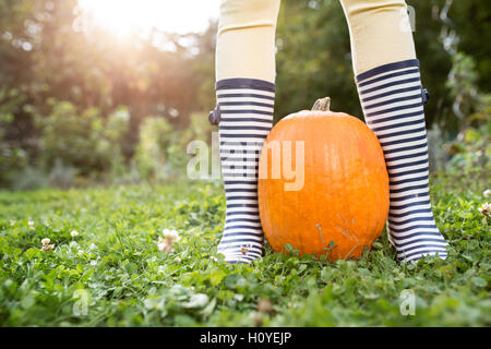 Irriconoscibile la donna a strisce in stivali di gomma con la zucca arancione Foto Stock