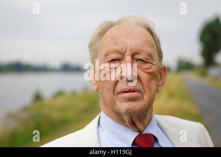 Senior uomo 80 in posa di fronte fiume, vicino up shot in estate guardando discutibile Foto Stock