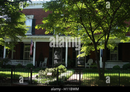 Lo stile del sud casa in Virginia, con vista del portico, con bandiera americana e bianco sedia a dondolo Foto Stock