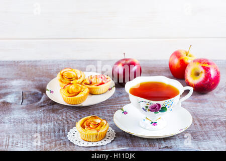 Tazza di tè e apple rose muffin sagomato sulla tavola in legno rustico. Dolce dessert apple pie. In casa apple pasticceria Rosa. Prima colazione Foto Stock