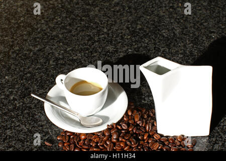 Sunshine colpendo la mattina caffè espresso e cappuccino con fagioli sul banco di marmo nero top Foto Stock