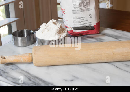 Il marmo spianatoia con misurazione di tazze di farina terrina e perno di rotolamento con luce naturale proveniente da una finestra Foto Stock