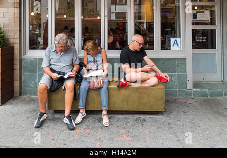 Turisti anziani che guardano guide, una mappa e uno smartphone su Prince Street a Lower Manhattan Foto Stock