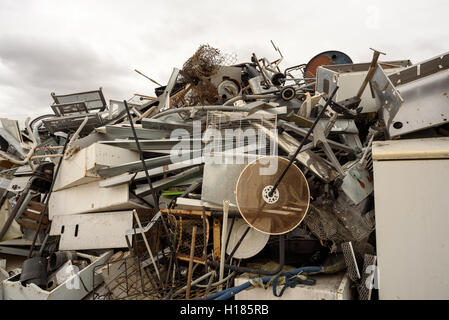 Rotto mucchio di rottami di metallo e di rotte domestiche merci bianco a un dump di riciclaggio con un nuvoloso cielo deprimente Foto Stock
