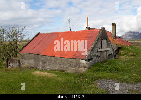 Parzialmente sepolti rosso coperto di stagno farm annessi nel sud dell'Islanda Foto Stock