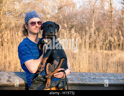 Ritratto di un giovane uomo tenendo un rottweiler cucciolo all'aperto Foto Stock