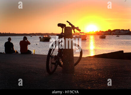 La foto perfetta- Bike stagliano contro il tramonto sul mare, Mudeford quay, Dorset, Regno Unito. Foto Stock