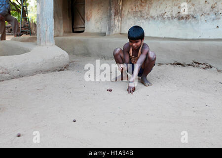 Un bambino che gioca il gioco di marmi, erdku village, chattisgarh, India Foto Stock