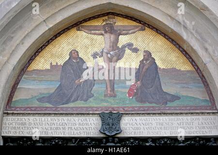 Lutherstadt Wittenberg, Germania. Xx Settembre, 2016. Una foto con Gesù sulla croce e Martin Luther (L) e Philipp Melantone inginocchiato al di sotto può essere visto sopra la porta con Lutero 95 tesi a tutti i santi della Chiesa in Wittenberg Lutherstadt Wittenberg, Germania, 20 settembre 2016. Nel 2017 la città celebra l'anniversario della riforma. Secondo la tradizione il teologo Martin Lutero (1483-1546) imbastito le sue 95 tesi contro la Chiesa " vendita di indulgenze in tutti i Santi Chiesa Wittenberg il 31 ottobre 1517. Foto: Jan Woitas/dpa/Alamy Live News Foto Stock