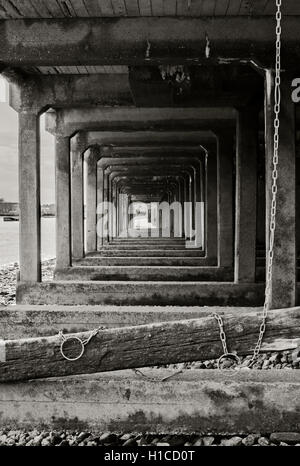 Lato terra pali di legno Wapping shore sotto il Boardwalk East di Londra sul Tamigi a bassa marea Tamigi Foto Stock