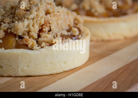 Trio di crostate di apple visualizzato su un striped tagliere di legno Foto Stock
