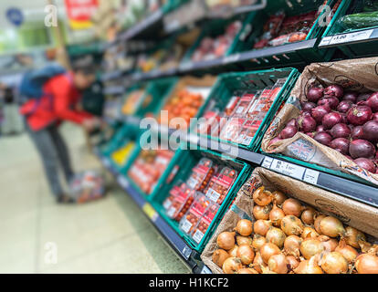 Cipolle in vendita nel supermercato produrre corsia con donna shopping sfocati sullo sfondo, REGNO UNITO Foto Stock