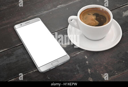 Smart phone sul tavolo di legno con isolati schermo bianco. Il caffè accanto a. Foto Stock
