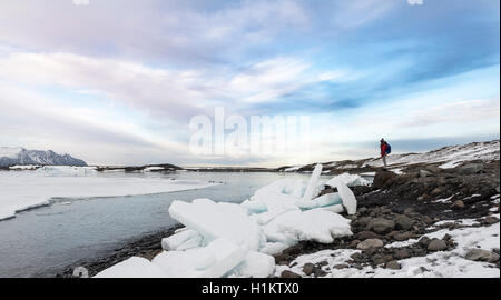 Donna in piedi accanto a ice floes, Jökulsárlón laguna glaciale, bordo meridionale del Vatnajökull, Regione orientale, Islanda Foto Stock