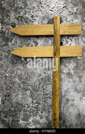 Due di legno cartelloni vuoto rivolta verso sinistra imperniata ad un posto contro un muro di pietra Foto Stock