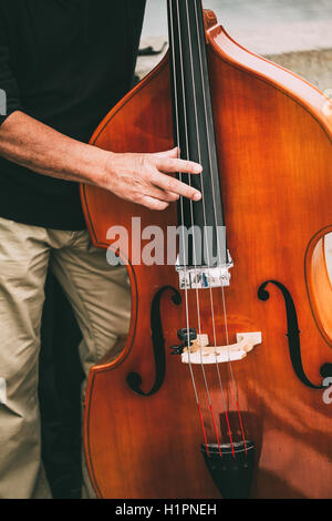 Suonatore ambulante di strada di eseguire musica Jazz all'esterno. Close Up di strumento musicale contrabbasso. Foto Stock