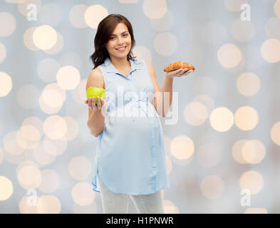 Felice donna incinta con Apple e croissant Foto Stock