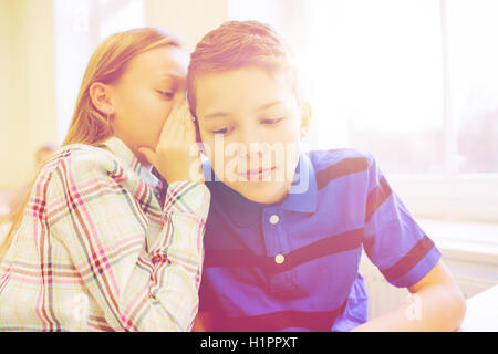 Sorridente schoolgirl whispering a classmate orecchio Foto Stock