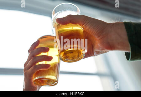 Close up di mani tintinnanti bicchieri da birra al pub Foto Stock