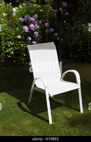 Sedie in plastica bianca nel giardino sul retro di una casa di famiglia. Foto Stock