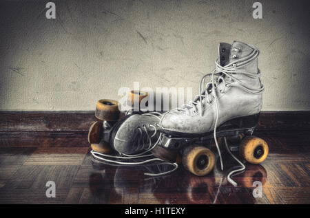 Vintage pattini a rotelle con grande scarpa-lacci su un muro sporco sullo sfondo Foto Stock