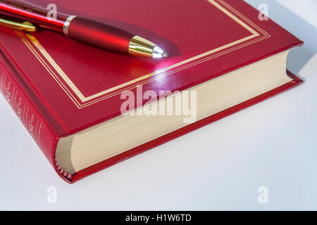 LED luce di penna a sfera giacente sul Libro rosso Foto Stock
