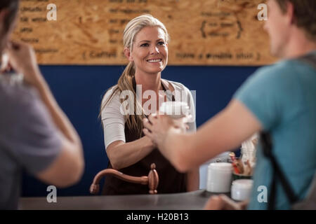 La donna in un cafe consegna monouso tazza di caffè Foto Stock