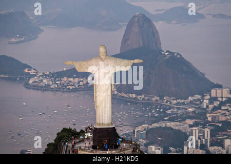 Cristo Redentore statua sul monte Corcovado guardando verso Sugarloaf e Baia Guanabara al tramonto a Rio de Janeiro in Brasile. Foto Stock