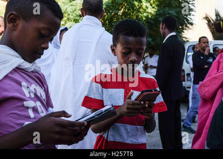 Gerusalemme, Israele. 24Sep, 2016. I ragazzi giocare con spartphones come cristiani africani, per la maggior parte provenienti da Etiopia ed Eritrea, convergono per la preghiera di sabato, a murata in Chiesa Etiope composto, costruito in più fasi tra il 1874 e il 1901. Credito: Nir Alon/Alamy Live News Foto Stock