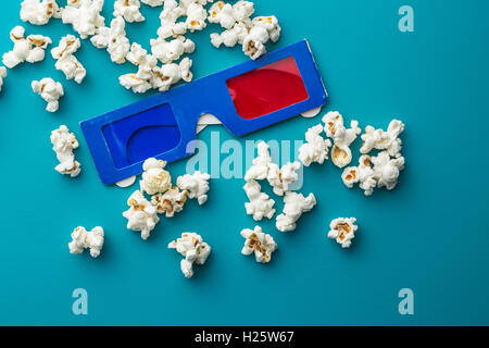 Popcorn e occhiali 3D su sfondo blu. Foto Stock