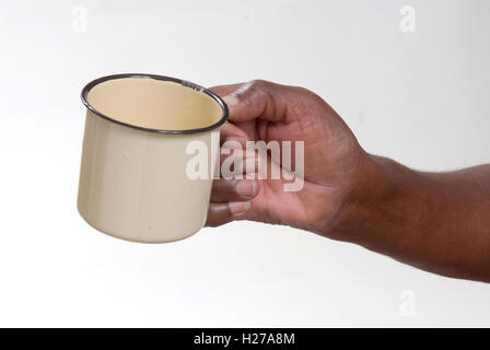African la mano che regge un vuoto di latta smaltata mug, potrebbe essere di accattonaggio o chiedere per bevande o alimenti Foto Stock