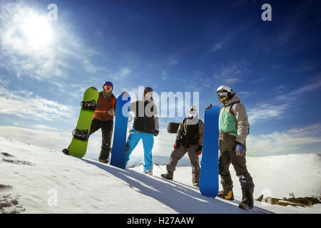 Gli appassionati di snowboard in posa sul cielo blu sullo sfondo di montagne Foto Stock