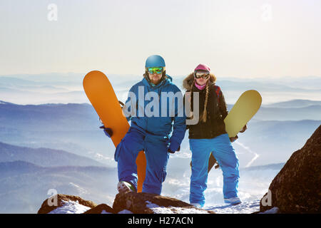 Gli appassionati di snowboard in posa sul cielo blu sullo sfondo di montagne Foto Stock